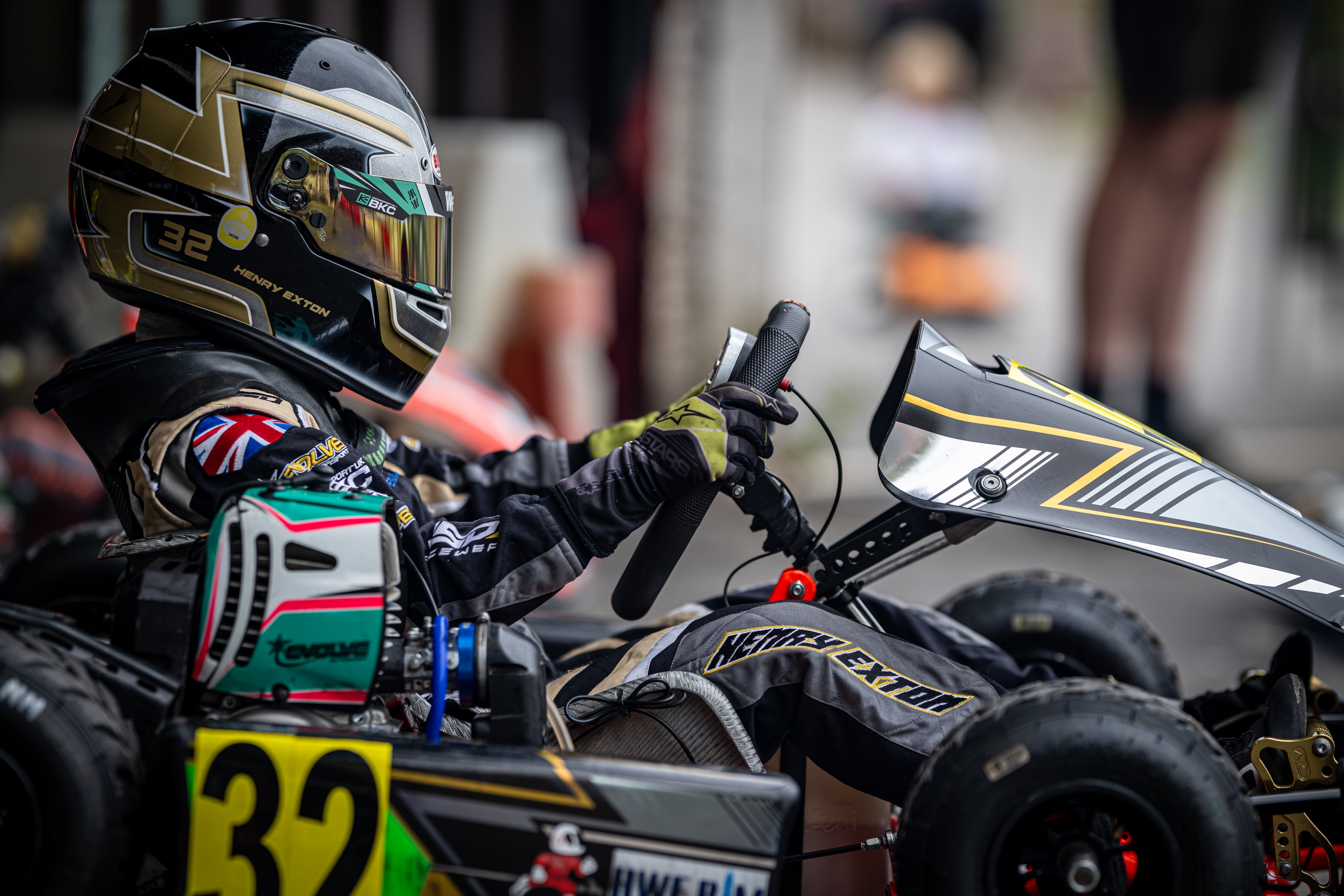Henry Exton in kart number 32 adjusting steering wheel in paddock at Rowrah