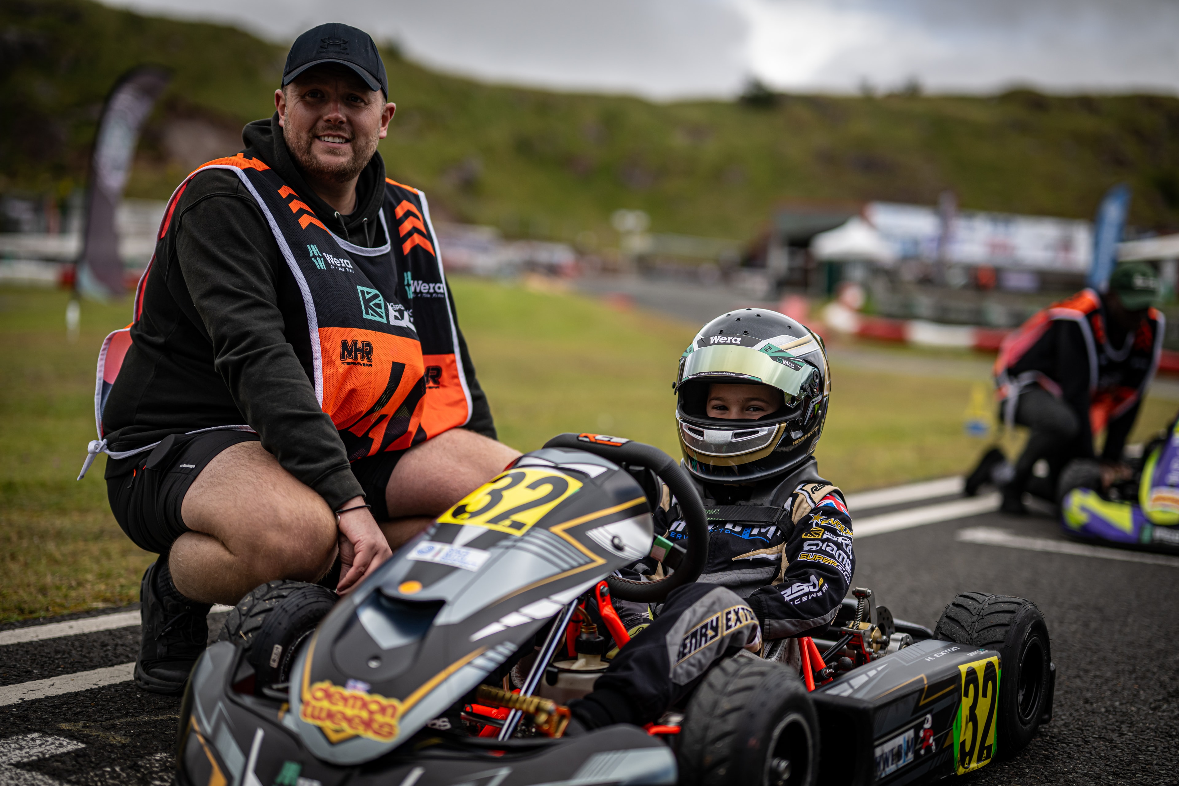 Henry Exton with mechanic kneeling beside kart number 32 on the grid at Rowrah