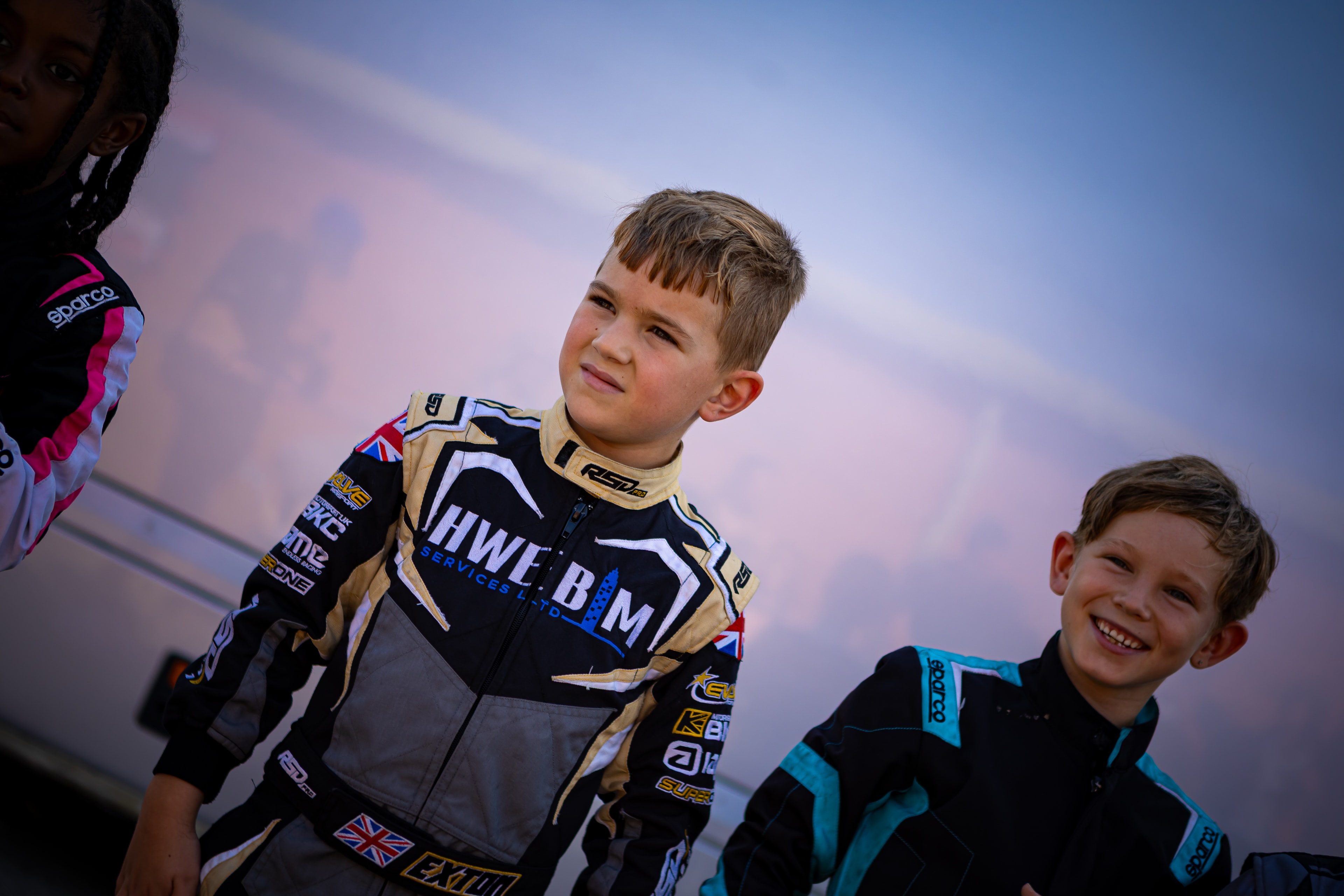 Henry Exton in race suit with HWE BIM Services branding at PFI paddock