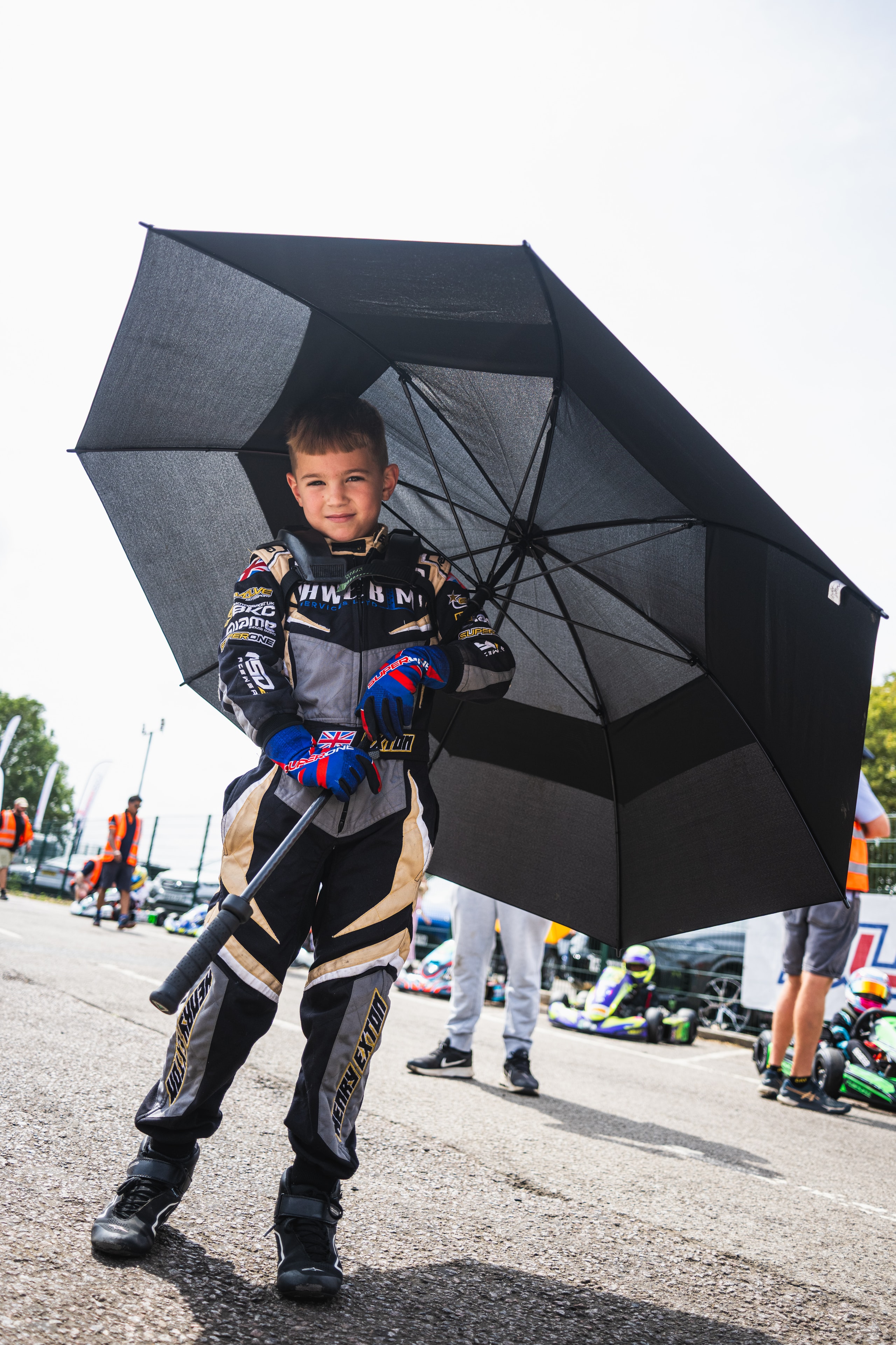 Henry Exton in race suit holding umbrella on the grid at Whilton Mill